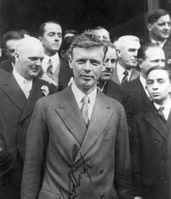 Black-and-white portrait photograph of Charles Lindbergh surrounded by a crowd in March 1928.